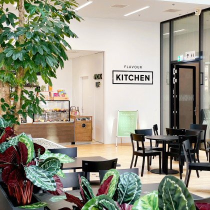 Bild Innenansicht Restaurant Flavour Kitchen in Bern mit Tischen bunten Pflanzen im Vordergrund und Theke im Hintergrund
