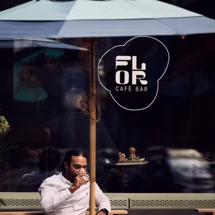 Mann sitzt auf einer Terrasse vor einem Fenster