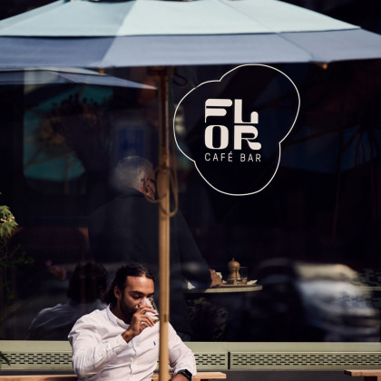 Mann sitzt auf einer Terrasse vor einem Fenster