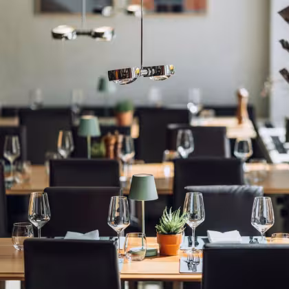 Restaurant Interieur mit dunklen Stühlen und gedeckten Tischen
