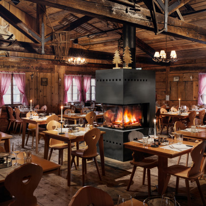 Innenansicht Fondue Chalet Zürichberg mit uriger alpiner Einrichtung aus Holz mit einem Kamin in der Raummitte