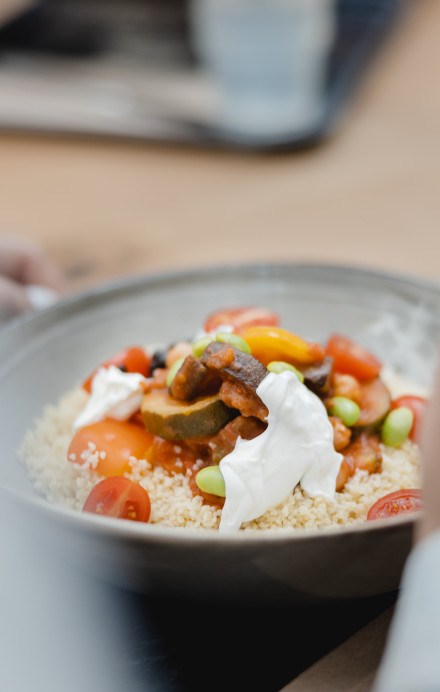 Ein Teller mit Couscous, diversem Gemüse und Joghurt auf einem Tablett