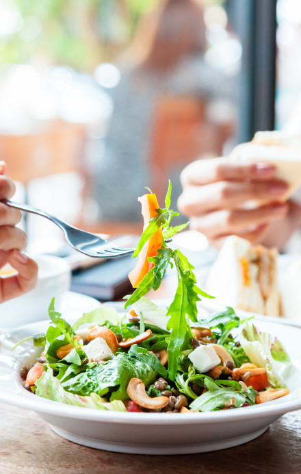 Businesslunch Sandwicht und Salat an einem Tisch mit hellem Tageslicht von rechts