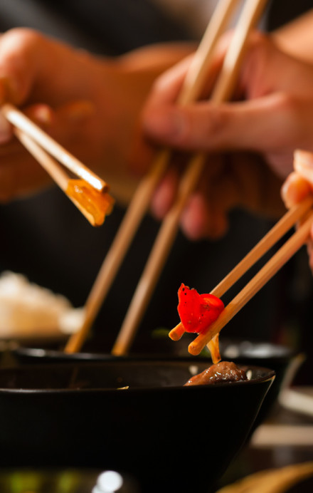 Personen essen asiatische Gerichte mit Stäbchen