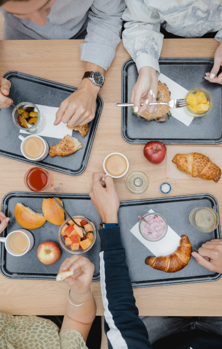 vier Personen sitzen an einem Tisch und frühstücken Gipfeli und Müesli