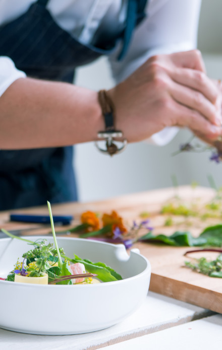 Küchenchef hält Kräuter in der Hand und bereitet das Essen vor