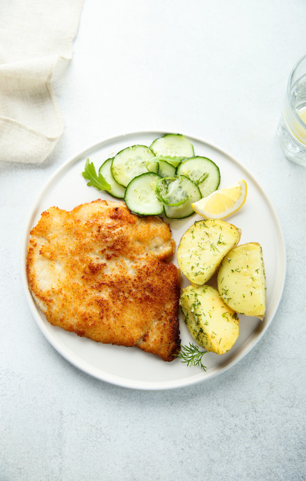 ein Teller mit Schnitzel, Kartoffeln und Gurken