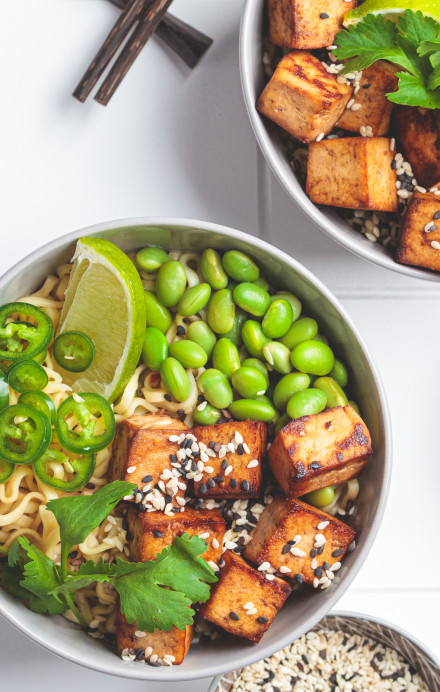 Zwei Bowls mit Nudeln, Tofu, Bohnen und Limetten