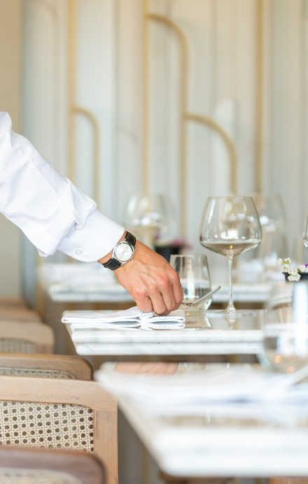 Tisch wird von einer männlichen Hand gedeckt im Restaurant