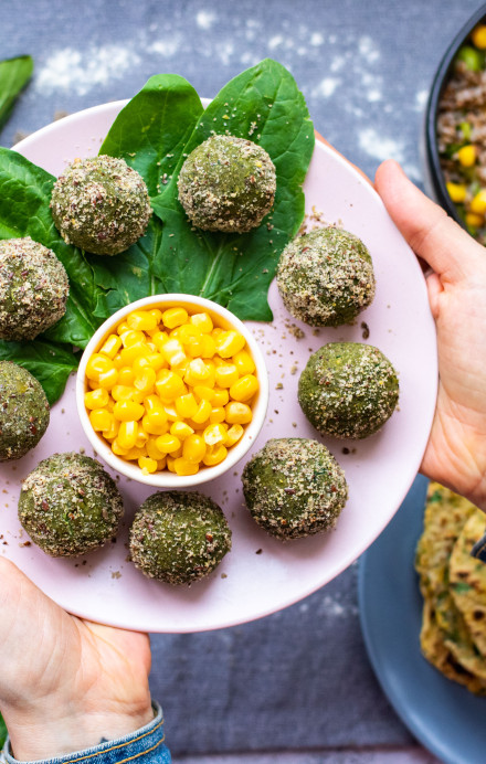 Bowl mit veganen grünen Falafel und Mais gehalten von Frauenhänden