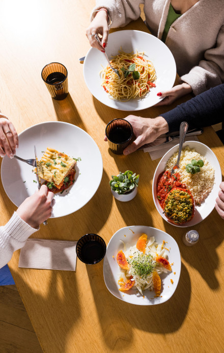 Tisch mit vier Gerichten und Menschen beim Essen