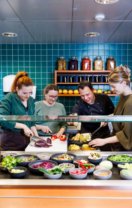 Team in einer Küche bereitet gemeinsam Essen zu