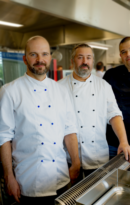 Vier Köche in Uniform in einer Gastronomieküche