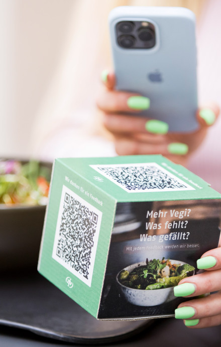 Frau scannt Würfel mit Handy, um ein Feedback abzugeben