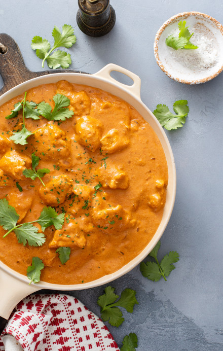 Tikka Masala mit Poulet in einer Pfanne, darum herum frische Zutaten