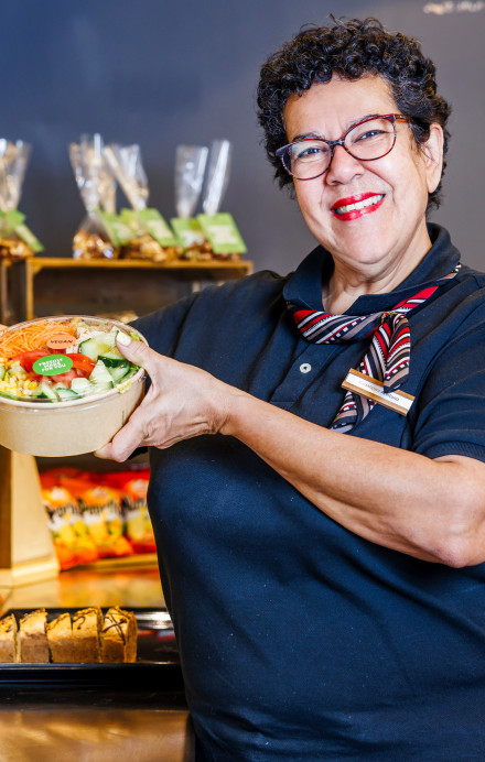 Frau nimmt einen Salat zum Mitnehmen aus einer Kühlvitrine