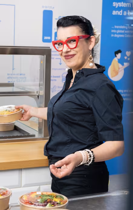 Frau stellt einen Salat in eine Vitrine