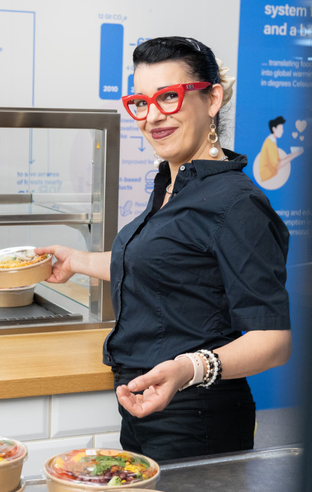 Frau stellt einen Salat in eine Vitrine