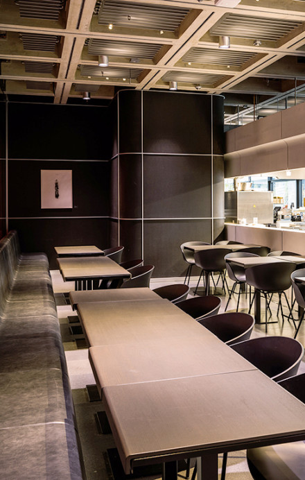 Innenansicht des SRF-Live Restaurants mit Glaswand direkt zum Studio. Einrichtung ist modern mit dunklen Tischen und Stühlen.
