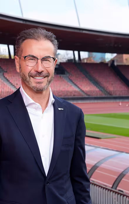Herr steht im Anzug in einem Schweizer Stadion