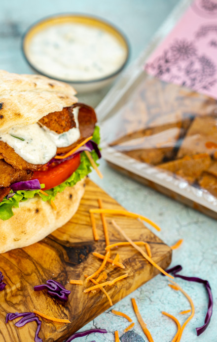 Pflanzenbasierter Döner mit Brot, dahinter eine Verpackung mit der Aufschrift Outlawz Food