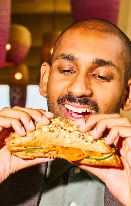 Mann beisst in ein Sandwich.