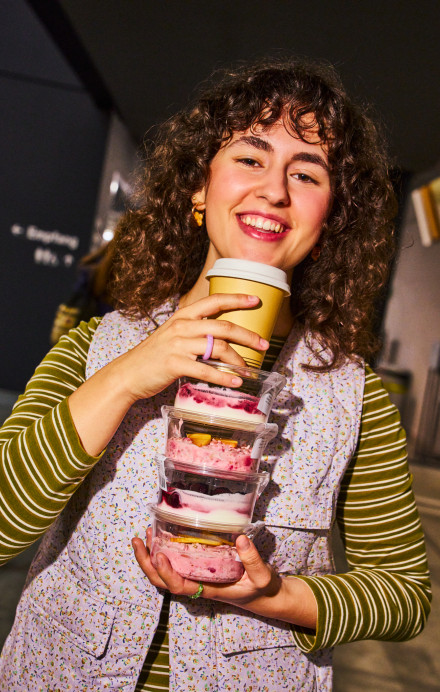 Eine junge Frau hält einen Turm aus Birchermüesli-Boxen.