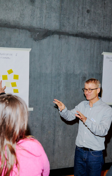 Personen beim Brainstorming vor einer Wand mit Post-its