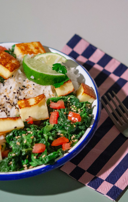 Teller mit Reisgericht und Spinat angerichtet auf einem Tisch