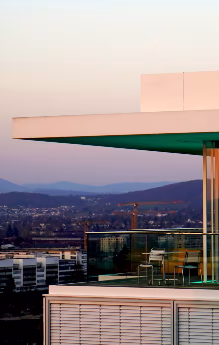Ansicht Dachterrasse des B1 Rooftop Bistros in Basel bei Sonnenuntergang und den Rôche Türmen im Hintergrund