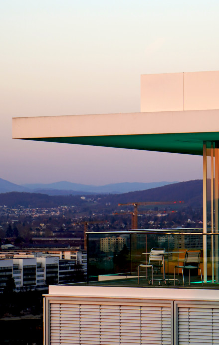 Ansicht Dachterrasse des B1 Rooftop Bistros in Basel bei Sonnenuntergang und den Rôche Türmen im Hintergrund