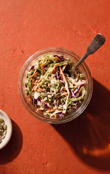 Weckglas mit Coleslaw, daneben liegen Kohl und Karotten
