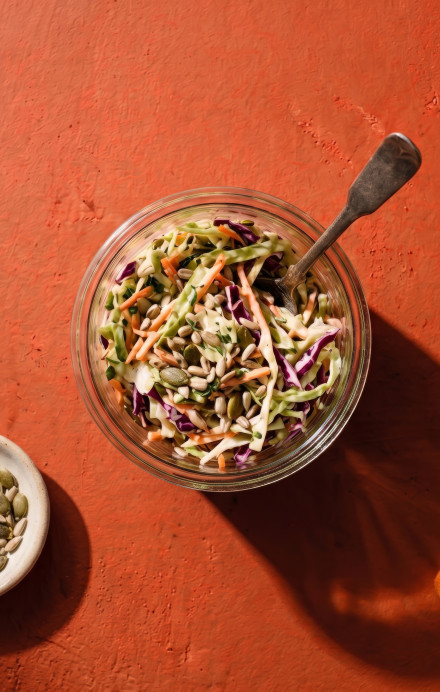 Weckglas mit Coleslaw, daneben liegen Kohl und Karotten