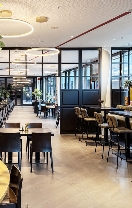Moderner Restaurantbereich der EY Platform Zürich mit Holztischen, Sitzgelegenheiten und grossen Fensterfronten.