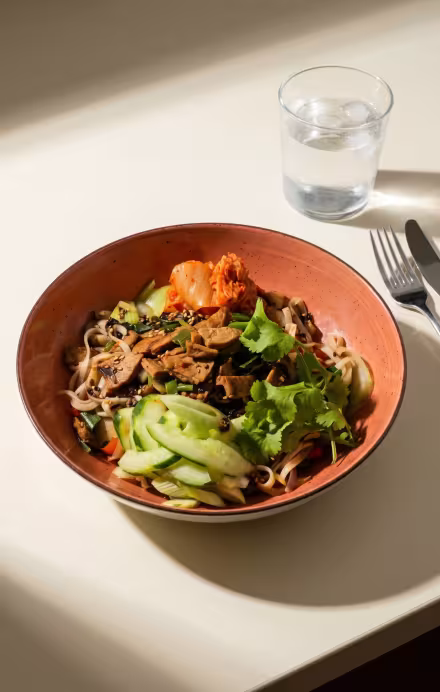 Oranger Teller mit Bibimbap auf einem Tisch