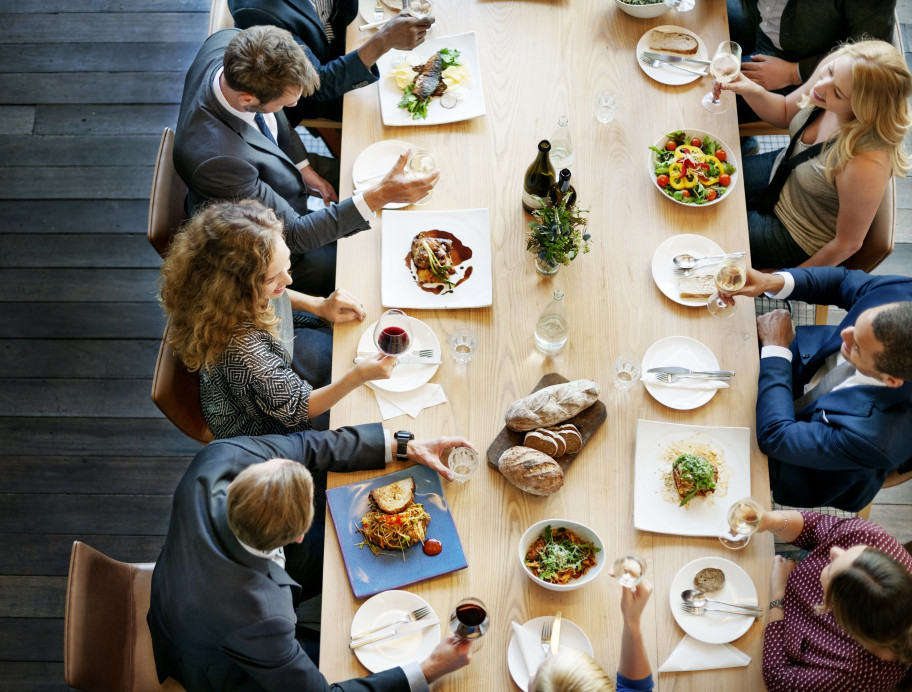 Personen an einem langen Tisch beim Mittagessen