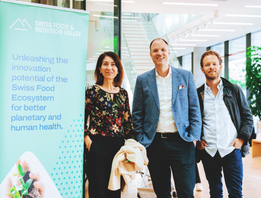 Drei Personen stehen vor einem Banner von SFNV