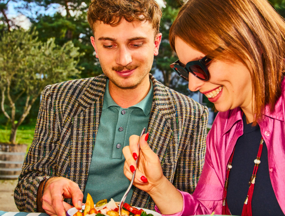 Frau und Mann sitzen in der Sonne und essen ihr Mittagessen.