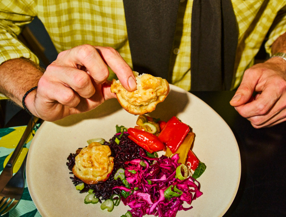 Teller mit Essen, männliche Hand hebt ein Stück hoch