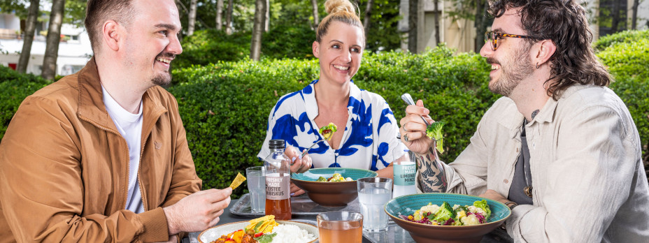Drei Personen essen auf einer Terrasse in der Sonne